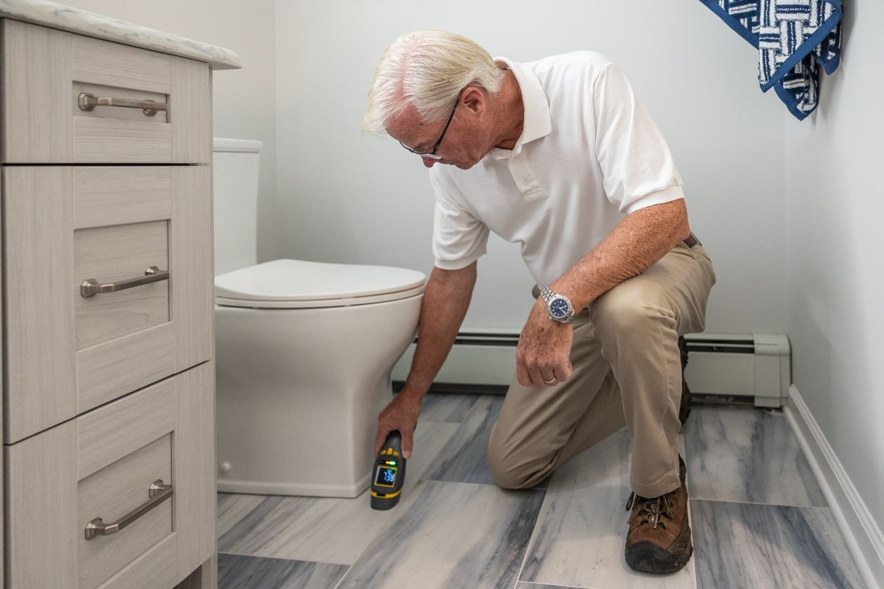 Older man inspecting a bathroom with a handheld device