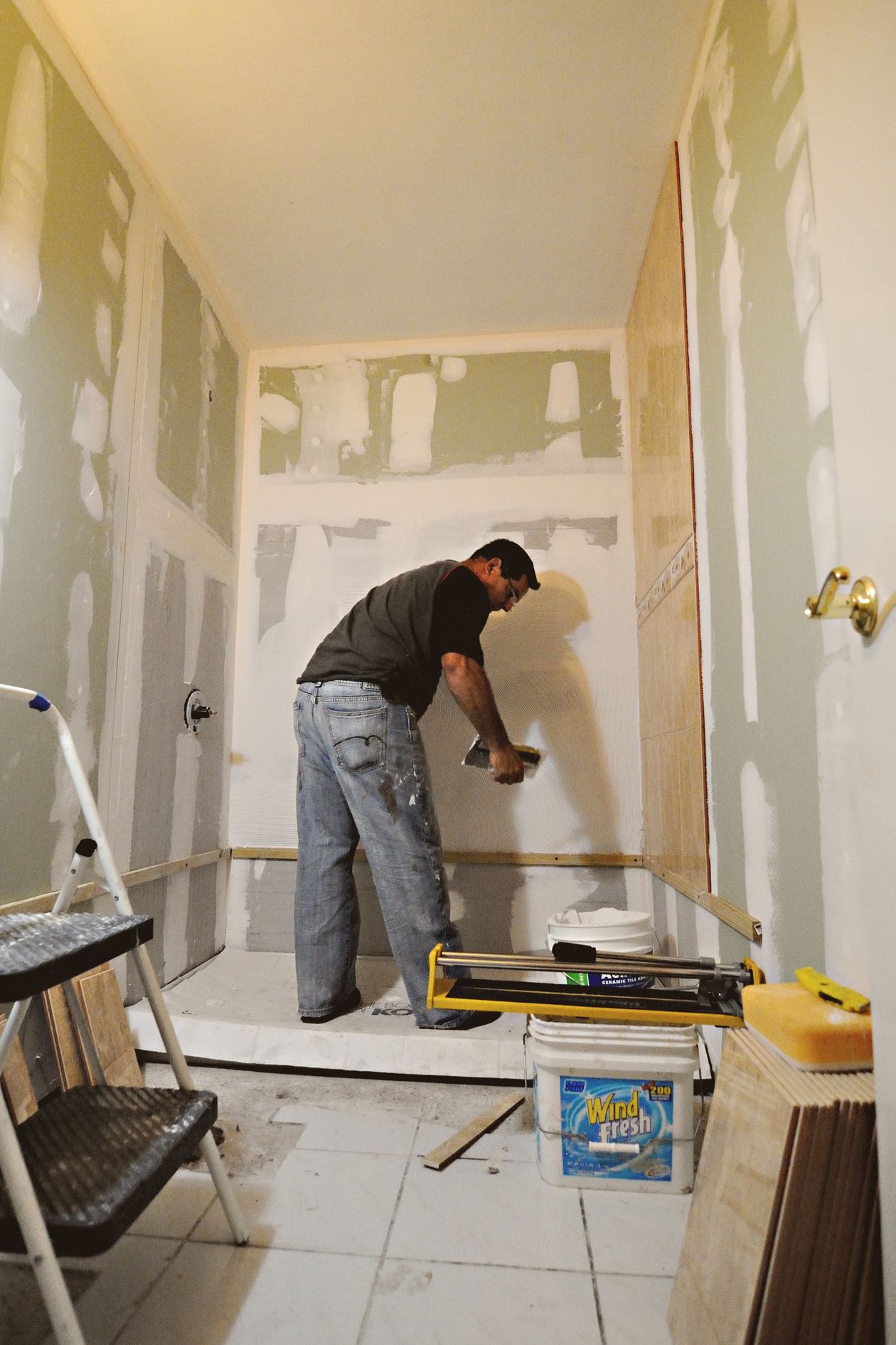Worker applying drywall compound to bathroom walls during a renovation