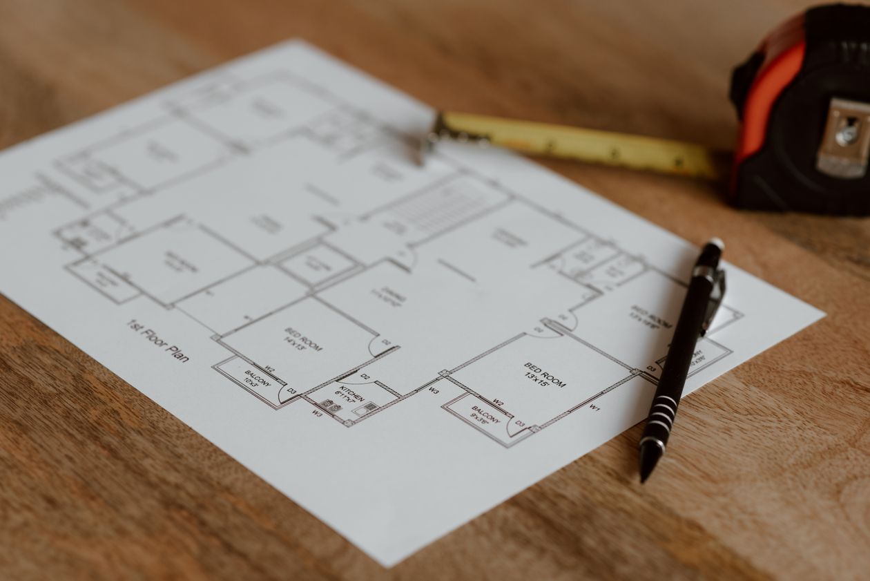 Floor plan on paper beside a pen and ruler on a wooden surface